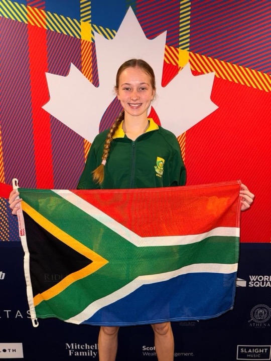 Vivienne van der Schyff holding the South African flag in front of the World Junior Championships backdrop